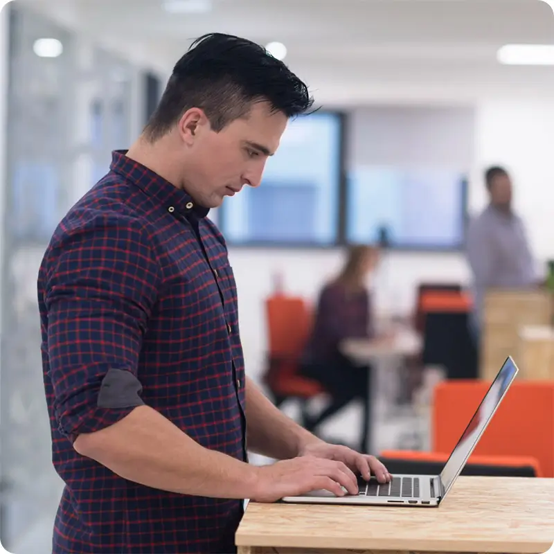 Man standing at desk working on laptop.